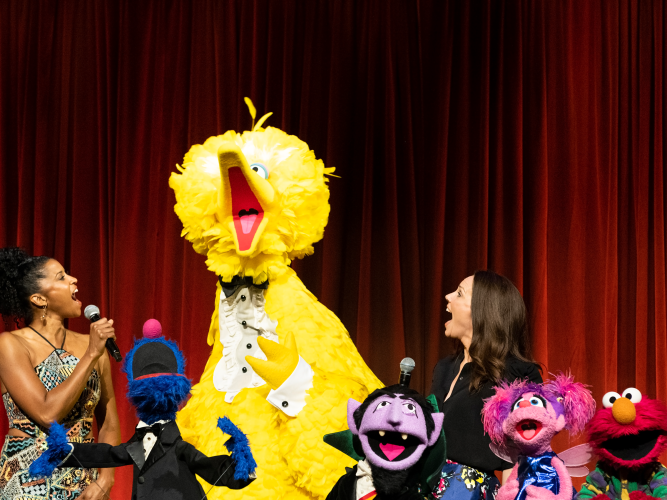 Renée Elise Goldsberry, Erica Hill, and the Sesame Street muppets sing together.