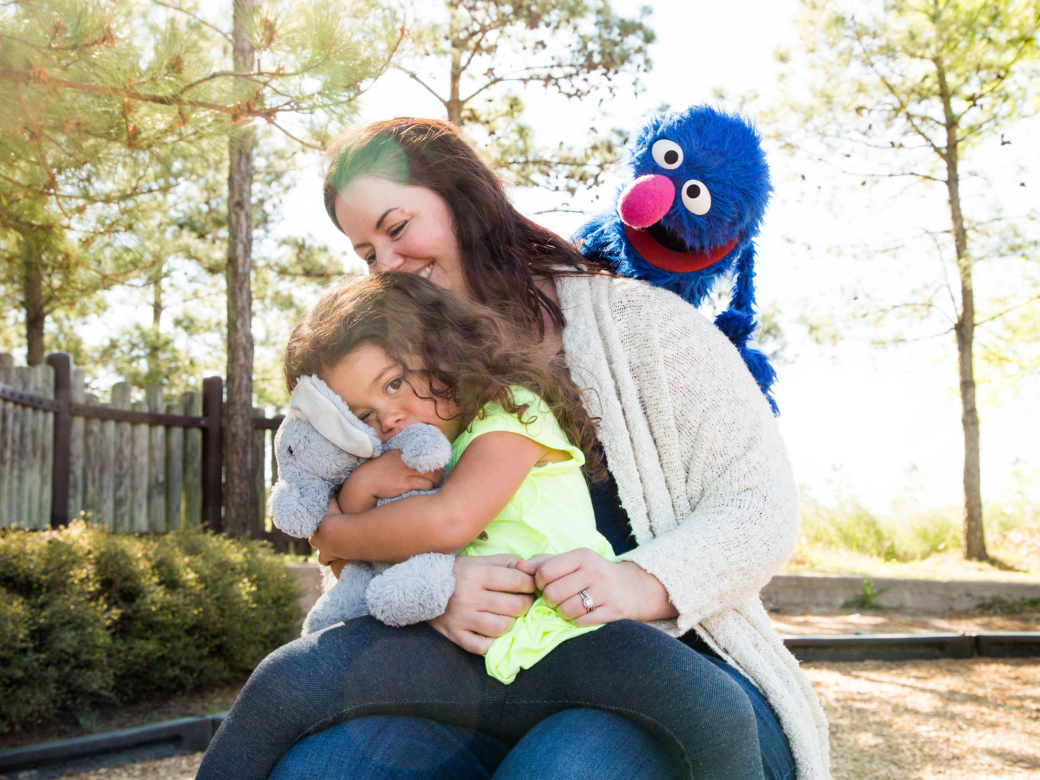 A mother and child hugging Grover.