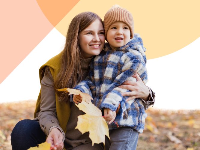 A parent and child holding Autumn leaves.