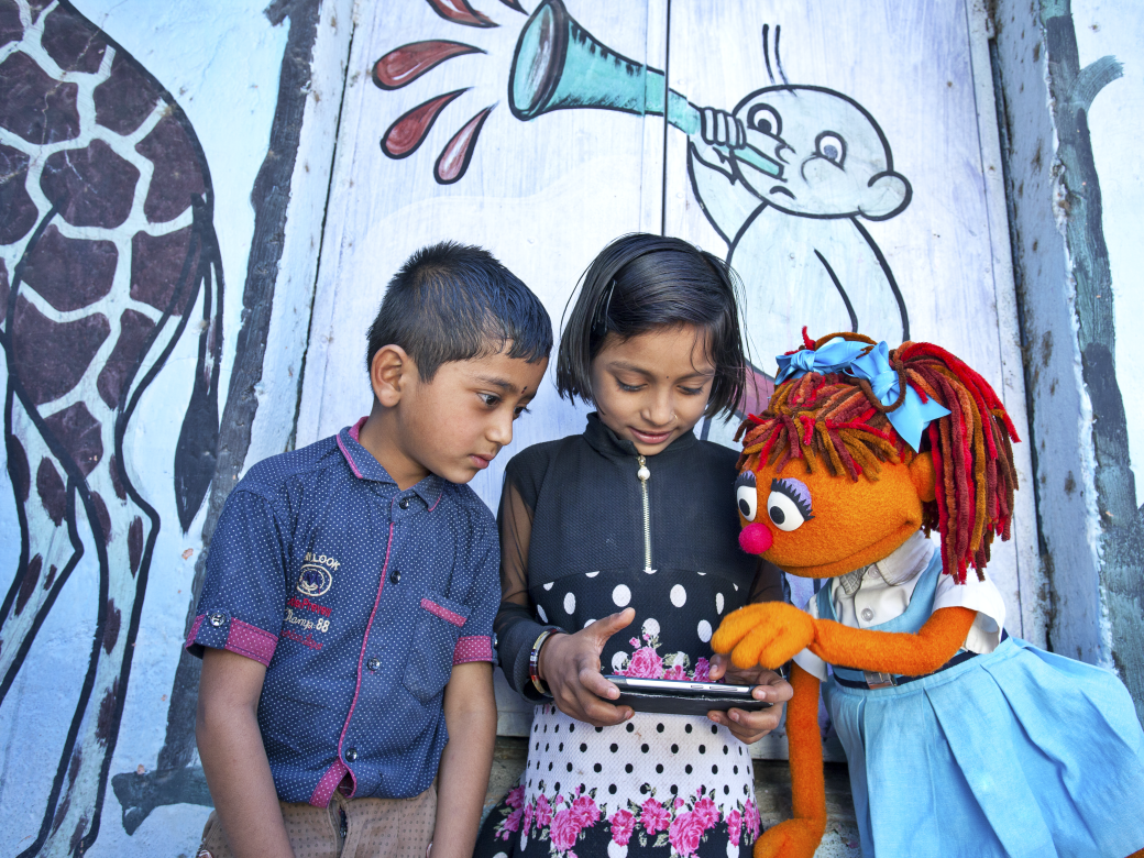 Chamki playing on a tablet with children.