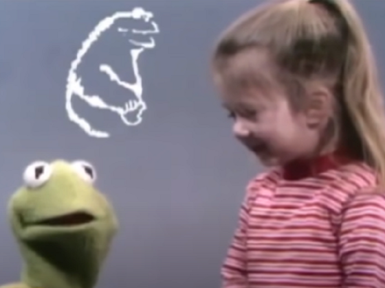 A child laughs with Kermit the Frog