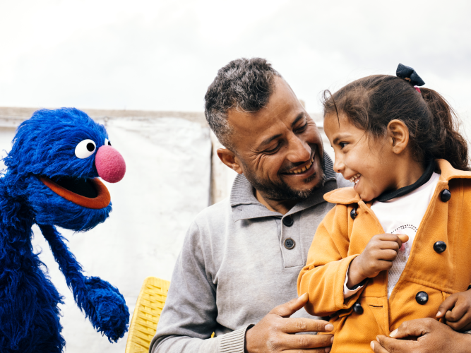 Grover smiling at a father and child.