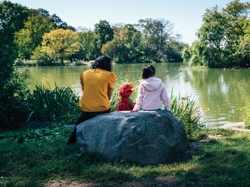 Elmo and a family sitting by a lake.