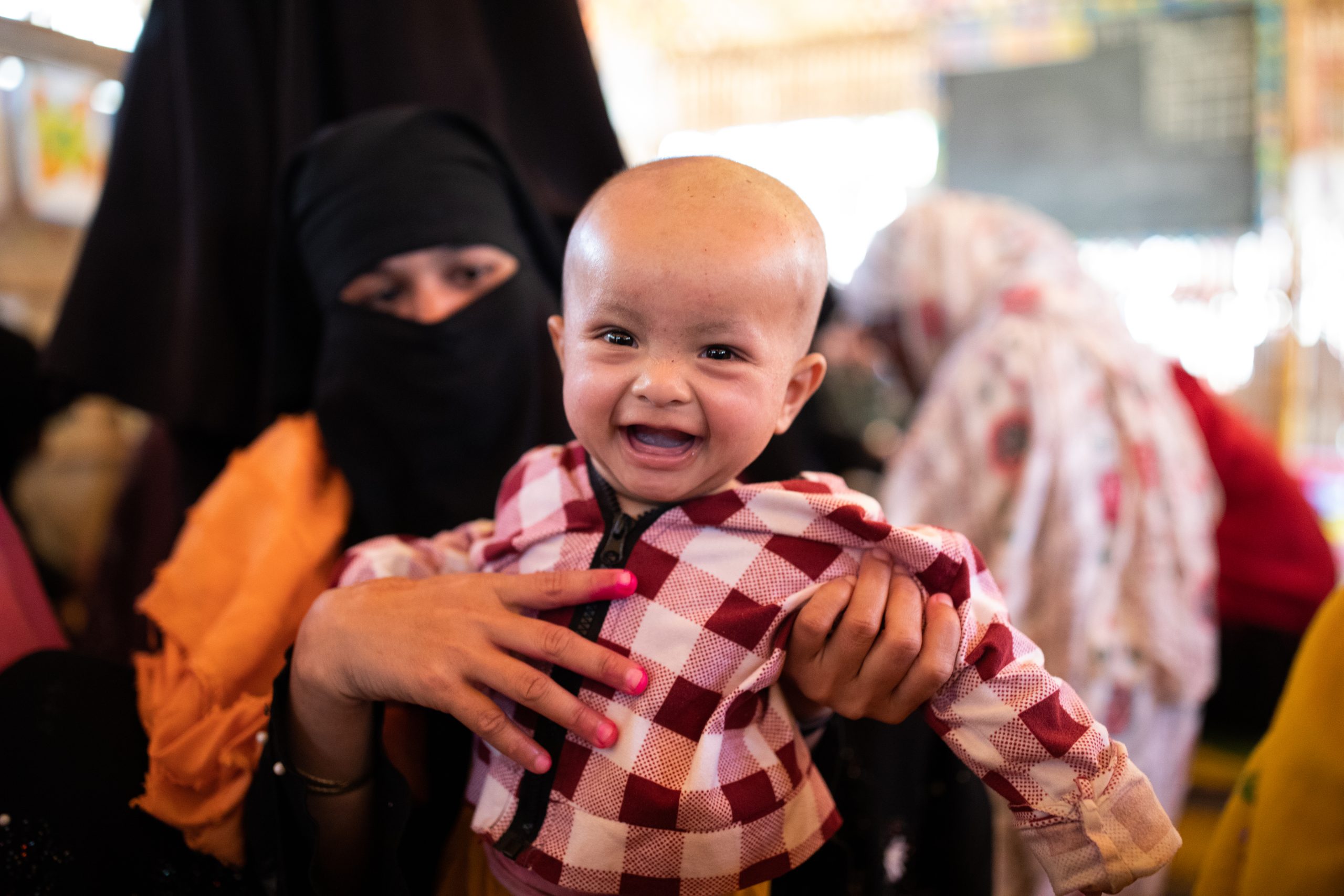 A caregiver holds up a smiling baby