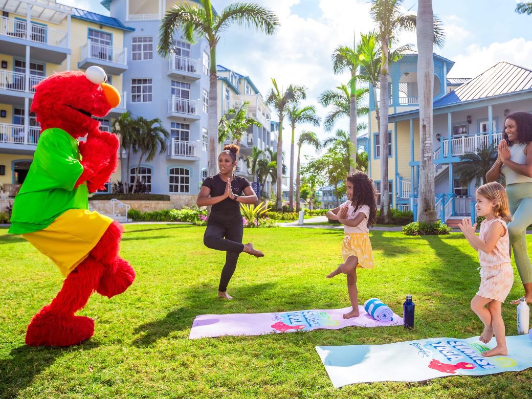 Elmo doing yoga with a group of people.