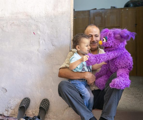 Basma plays with a baby and their parent