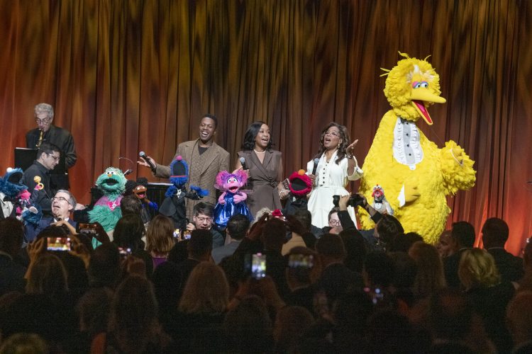 Oprah, Big Bird, Shonda Rhimes, Leslie Odom, Jr., and Elmo singing on stage.