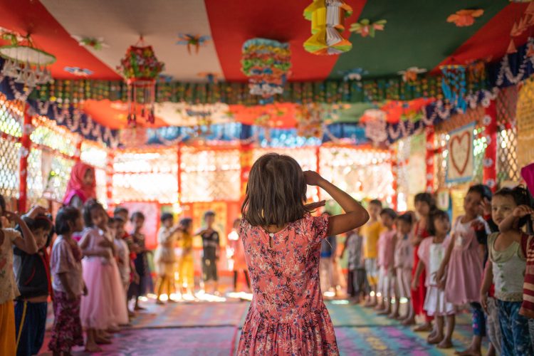 A child stands and looks at their classroom of peers