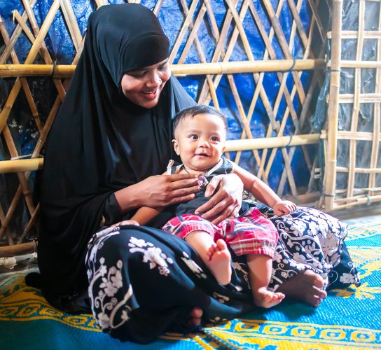 A mother holds her child and smiles