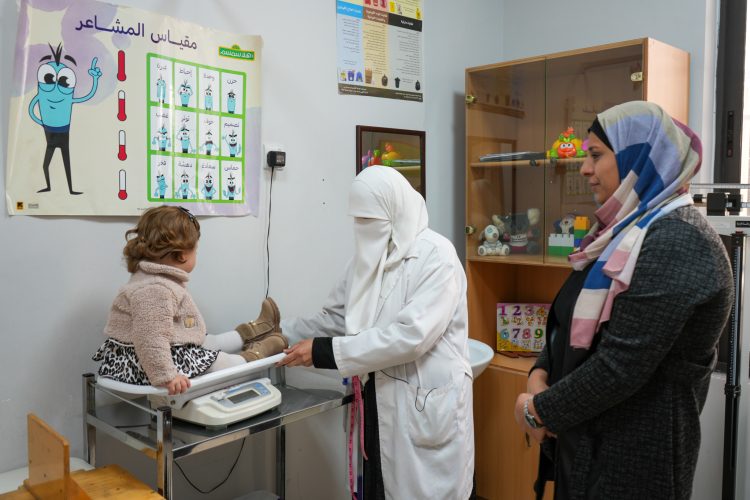 A doctor weighing a child as their parent watches.