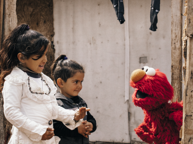 Elmo talking to two children.