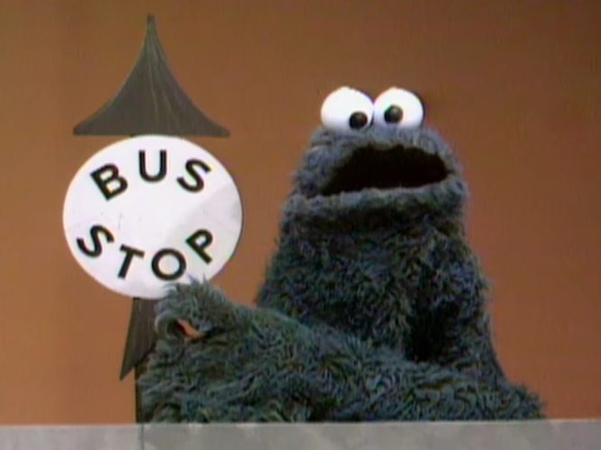 Cookie Monster with a bus stop sign.