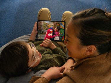 A parent and child looking at a tablet.