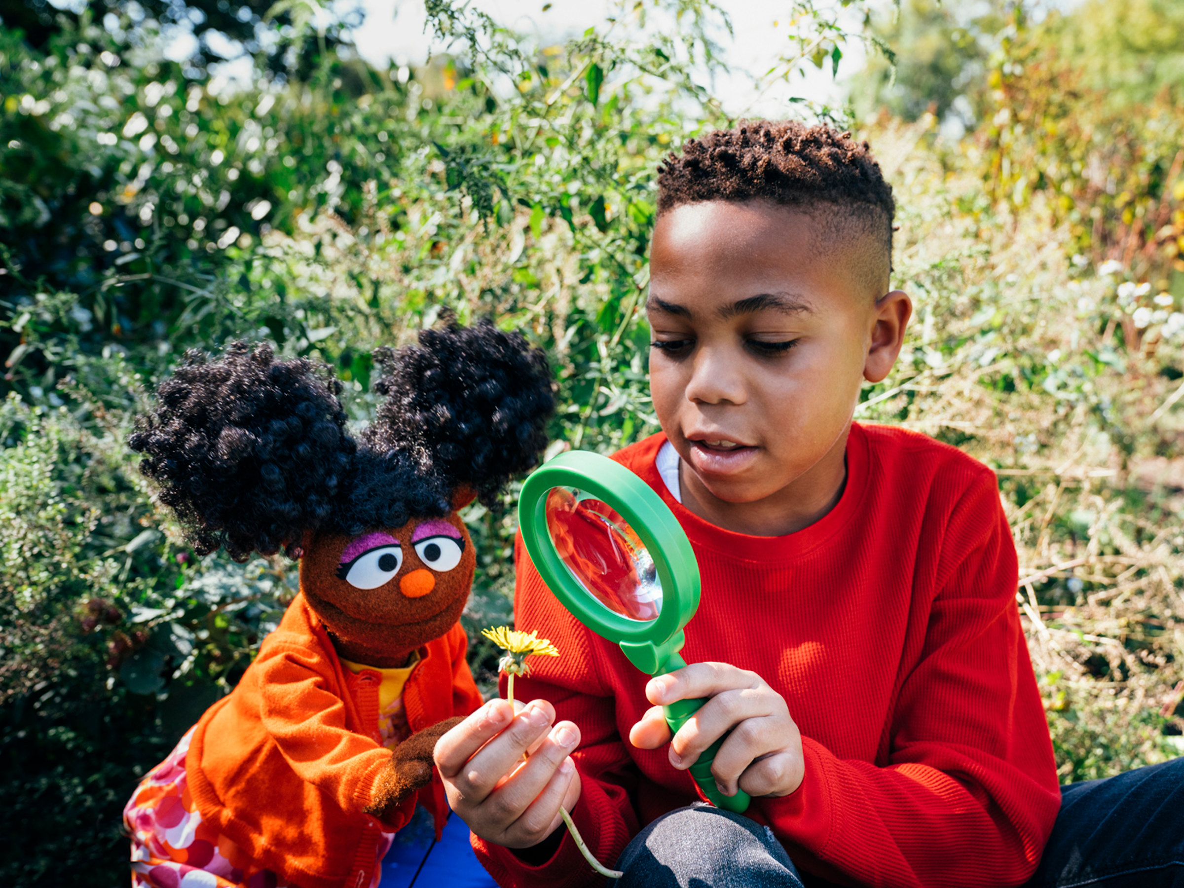 Child looking at flower through a magnifying glass.
