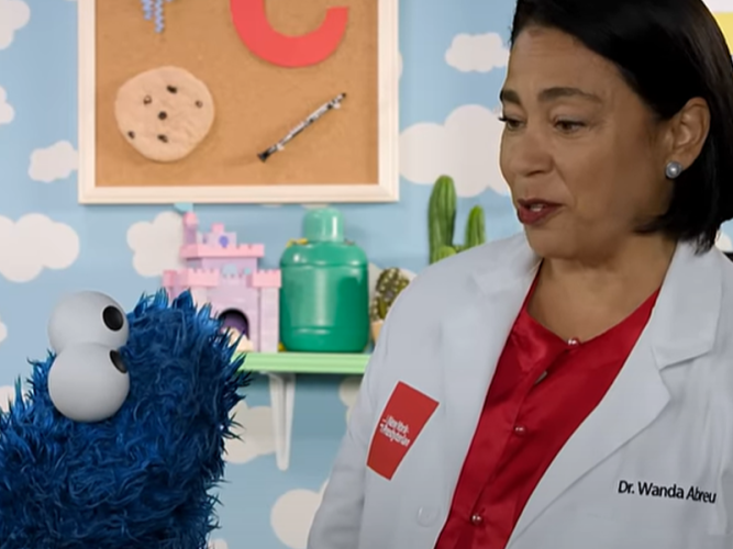 A doctor talking to Cookie Monster.