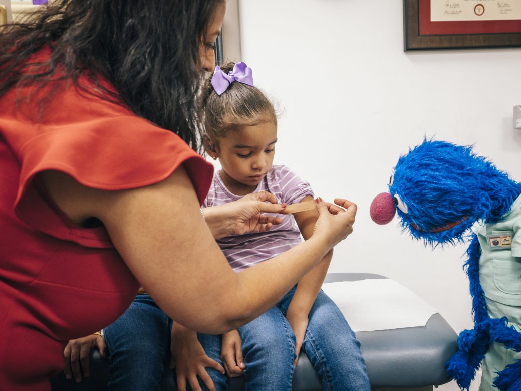A family and Grover in a healthcare setting.
