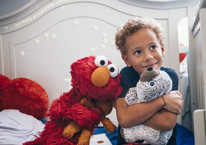 Elmo and a child hugging stuffed animals.