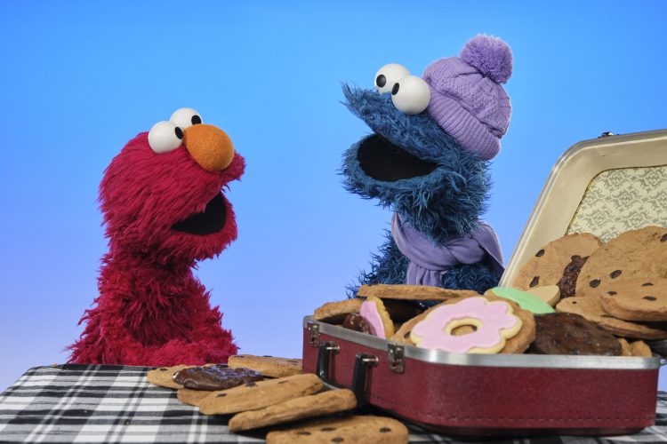 Elmo and Cookie with a suitcase full of cookies.