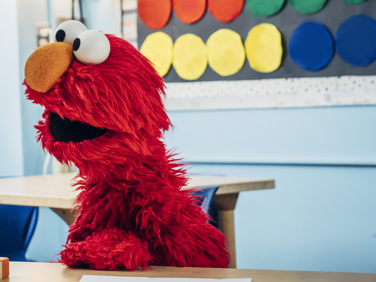 Elmo in a school with children.