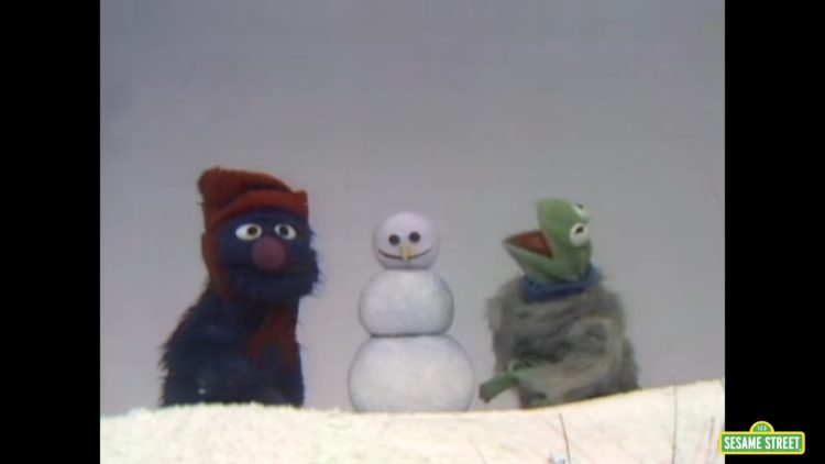 Kermit and Grover build a snowman.
