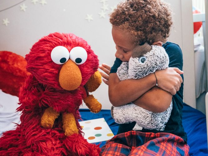 Elmo and a child hugging stuffed animals.