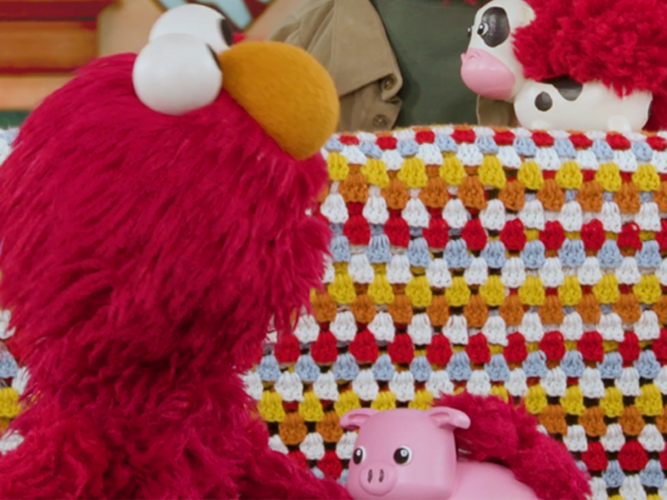 Elmo holding a piggy bank.