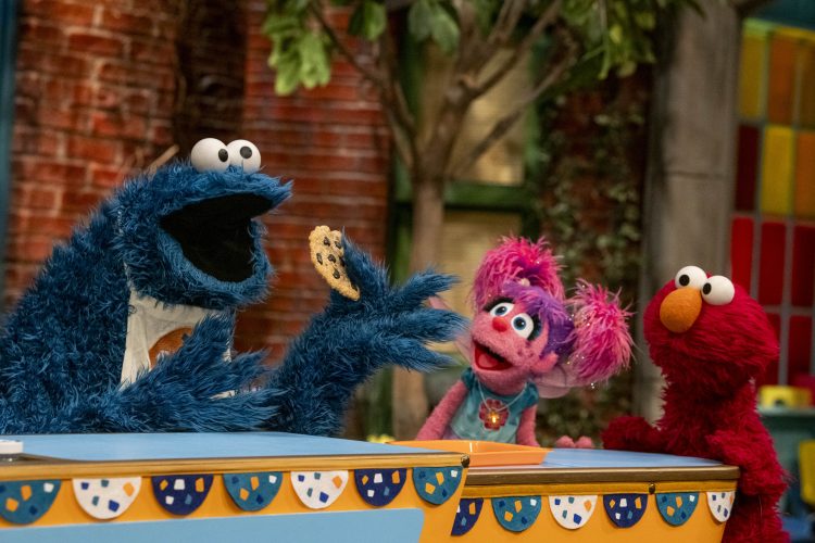 Cookie Monster holding a cookie with Abby and Elmo